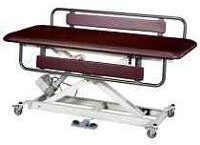 Adjustable medical examination table with a brown cushioned surface and metal frame on wheels.